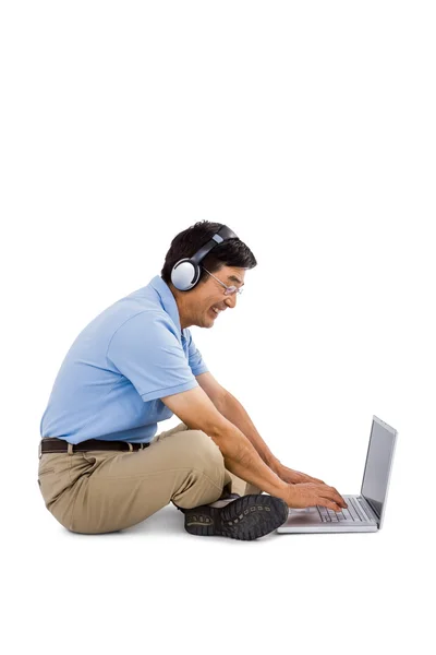 Χαρούμενος άνθρωπος ακούγοντας μουσική ενώ χρησιμοποιείτε φορητό υπολογιστή — Φωτογραφία Αρχείου