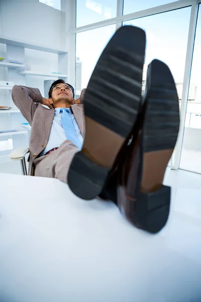 Empresário bem sucedido relaxando com os pés em sua mesa — Fotografia de Stock