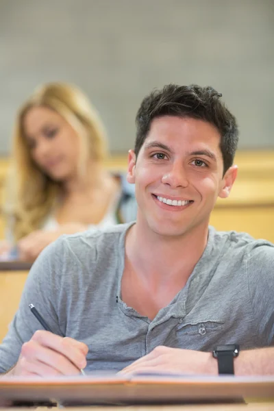 Gülümseyen erkek öğrenci sınıf sırasında — Stok fotoğraf