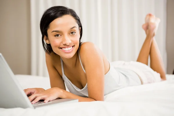 Lachende brunette met behulp van laptop — Stockfoto