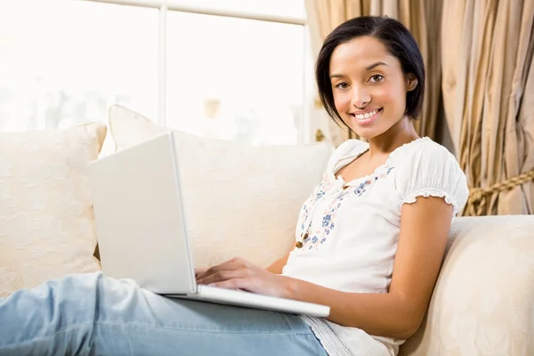 Brunette using laptop on the sofa — Stock Photo, Image