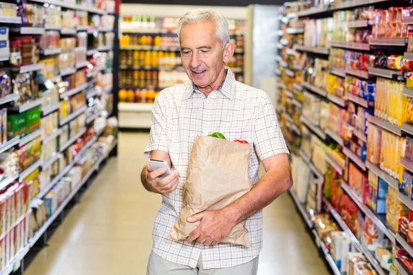 Mann mit Einkaufstasche benutzt Smartphone — Stockfoto