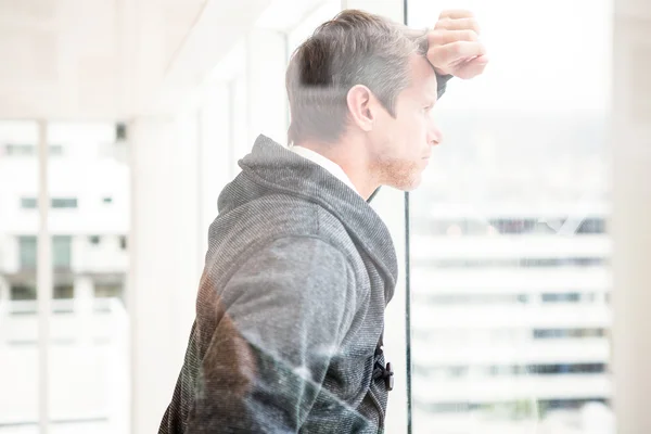 Thoughtful man leaning on glass window — Stock Photo, Image