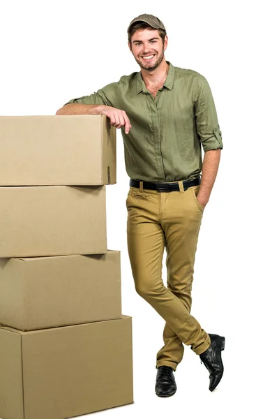 Handsome postman standing by cardboard boxes — Stock Photo, Image