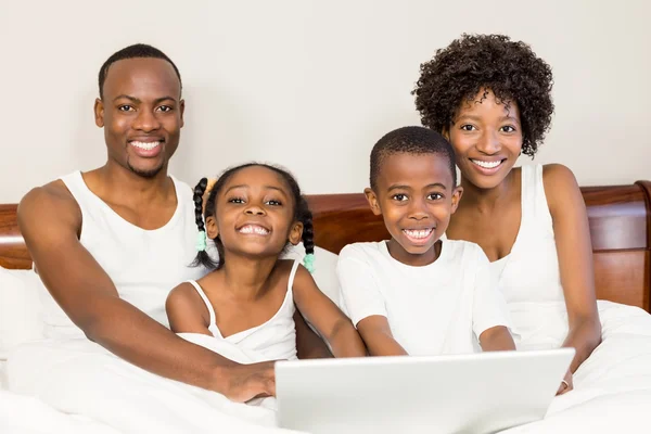 Família feliz deitada na cama juntos — Fotografia de Stock