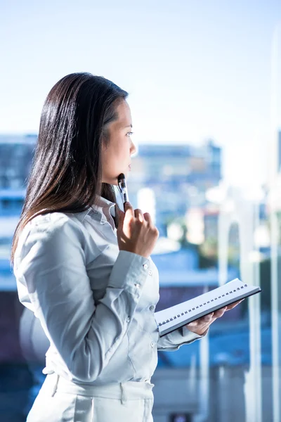 Thoughtful woman with pen on cheek — Stock Photo, Image