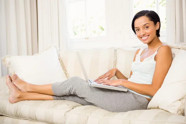 Lachende brunette met behulp van laptop — Stockfoto