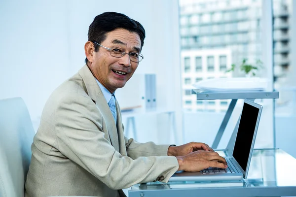Lachende Aziatische zakenman die op laptop werkt — Stockfoto