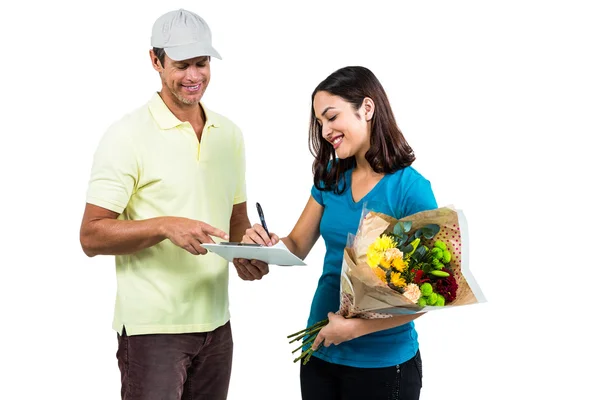 Woman signing on clipboard while receiving bouquet — Stock Photo, Image