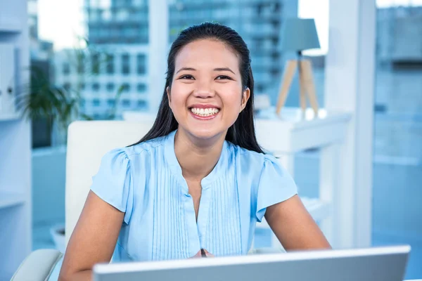 Empresária sorridente trabalhando em sua mesa — Fotografia de Stock