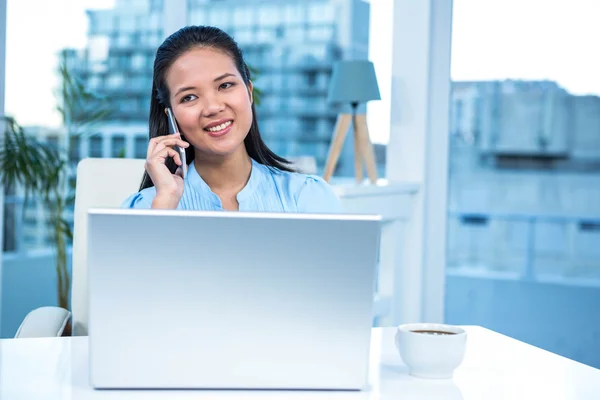 Glimlachende zakenvrouw op telefoon via laptop — Stockfoto