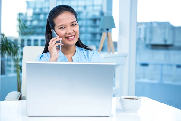 Mujer de negocios sonriente en el teléfono usando el ordenador portátil — Foto de Stock