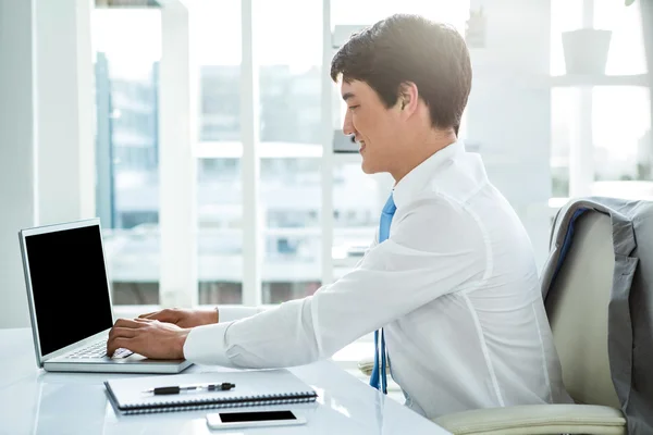 Lachende Aziatische zakenman die op laptop werkt — Stockfoto