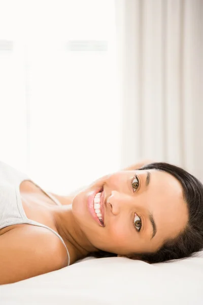 Lächelnde Brünette auf dem Bett liegend — Stockfoto