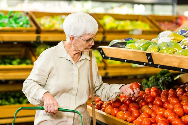 Senior vrouw plukken uit sommige groenten — Stockfoto