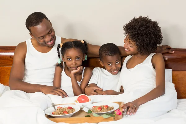 Happy family lying in bed together — Stock Photo, Image