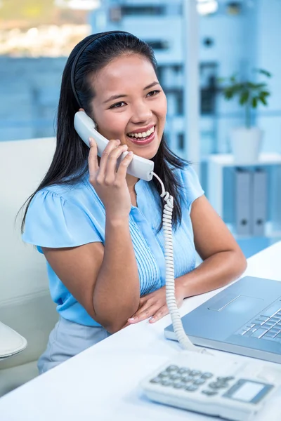 Mujer de negocios sonriente usando teléfono fijo — Foto de Stock