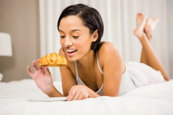 Senyum brunette makan croissant — Stok Foto