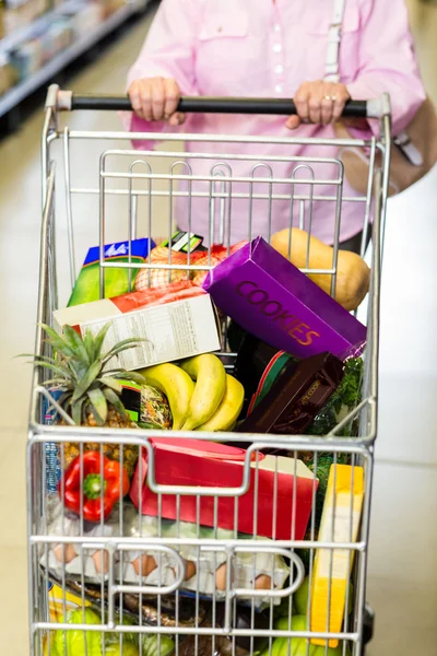 Senior vrouw duwen volledige kar — Stockfoto