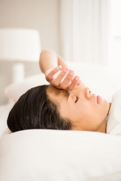 Frowning brunette in bed — Stock Photo, Image