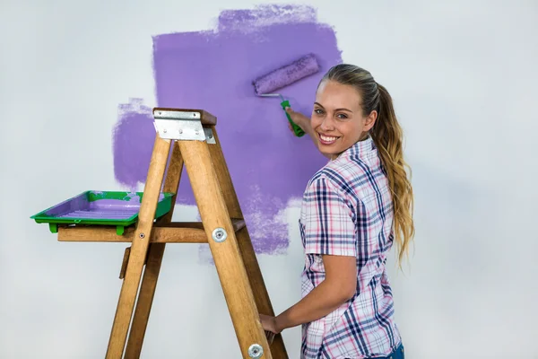 Leende kvinna måla en vägg — Stockfoto