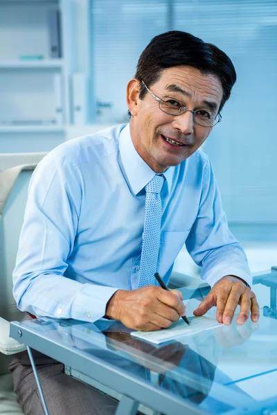 Glimlachend Aziatische zakenman ondertekening document — Stockfoto