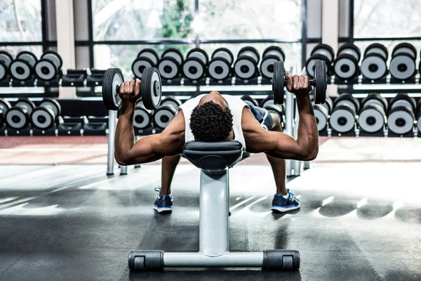 Muscular man lifting dumbbells — Stock Photo, Image