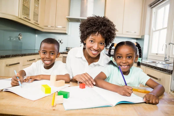 Madre ayudando a los niños a hacer su tarea — Foto de Stock