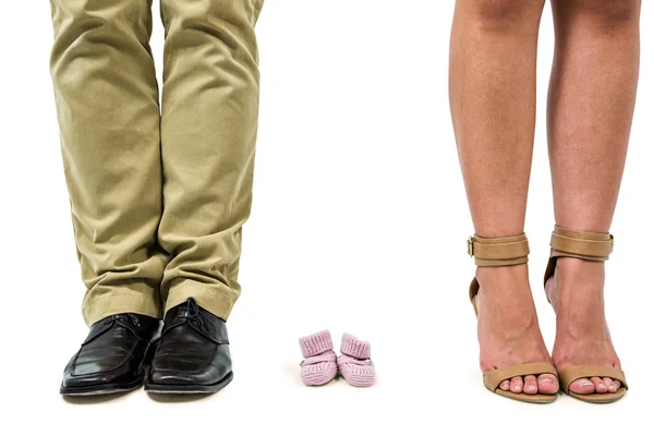 Close-up of man and woman amidst baby shoes — Stock Photo, Image