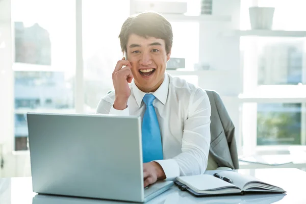 Lachende Aziatische zakenman die op laptop werkt — Stockfoto