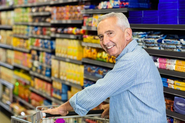 Smiling senior man pushing trolley — Stock Photo, Image