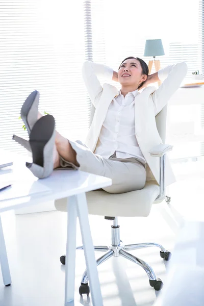 Empresária relaxante com as pernas na mesa — Fotografia de Stock