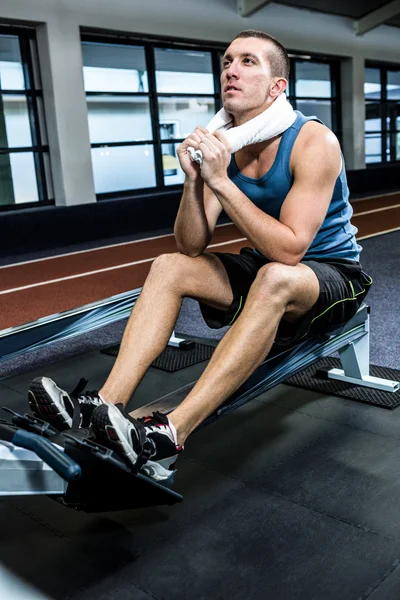 Hombre muscular usando máquina de remo — Foto de Stock