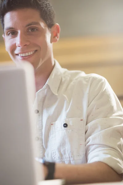 Lachende mannelijke student met behulp van laptop — Stockfoto