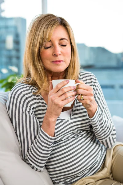 Frau hält Tasse auf Sofa — Stockfoto