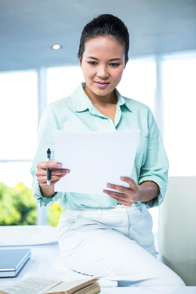 Mujer de negocios sonriente sentada en su escritorio —  Fotos de Stock