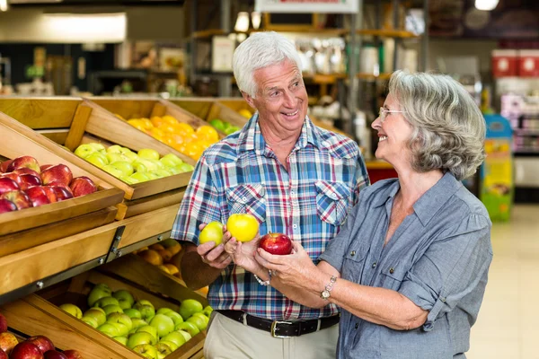 Улыбающаяся пожилая пара держит яблоки — стоковое фото