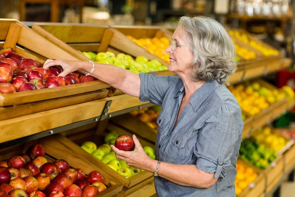 Улыбающаяся пожилая женщина собирает яблоки — стоковое фото