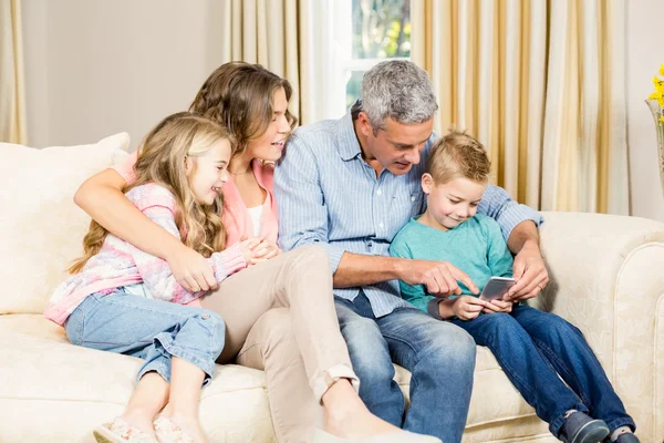 Famille heureuse utilisant le téléphone sur le canapé — Photo