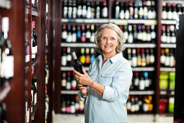 Sorridente donna anziana che sceglie il vino — Foto Stock