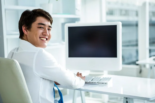 Lachende Aziatische zakenman met behulp van zijn computer — Stockfoto