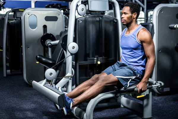 Hombre muscular usando máquina de ejercicio — Foto de Stock