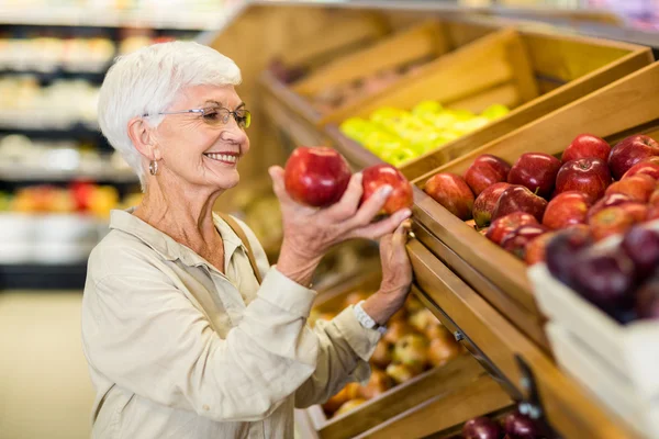 Mujer mayor recogiendo manzana roja — Foto de Stock