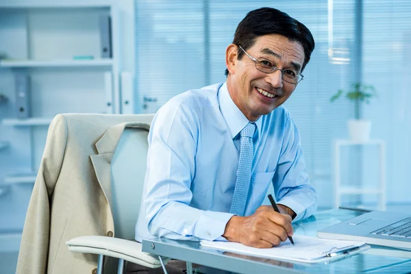 Lachende Aziatische zakenman, het schrijven van een verslag — Stockfoto