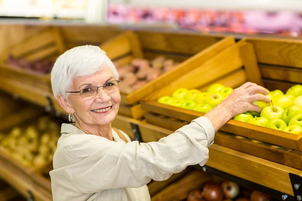 Старшая женщина выбирает зеленое яблоко — стоковое фото
