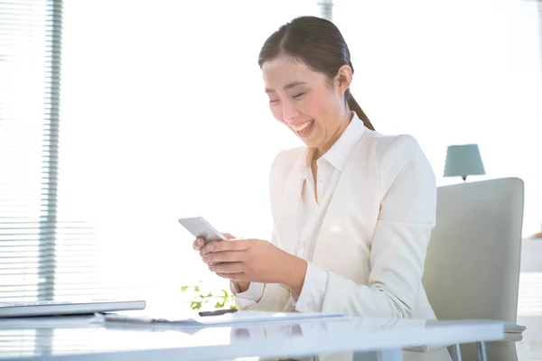 Улыбающаяся деловая женщина пишет смс на телефон — стоковое фото