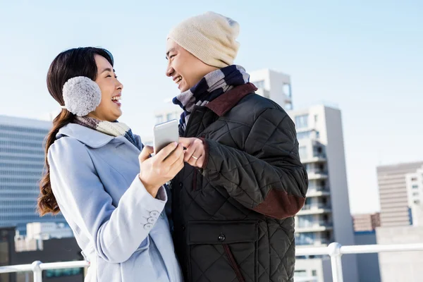 Pareja riendo mientras sostiene el teléfono inteligente — Foto de Stock