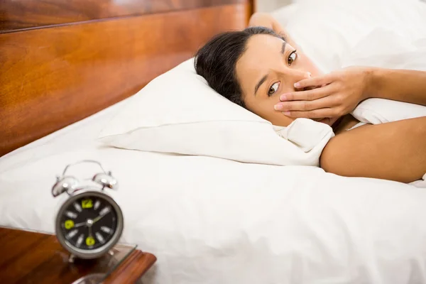 Morena na cama olhando para o despertador — Fotografia de Stock