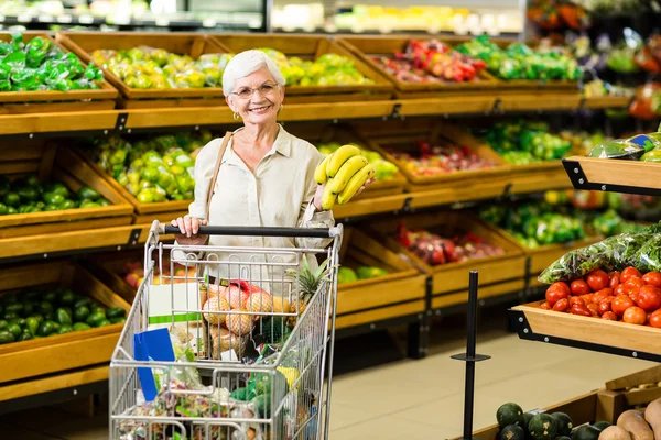 Senior vrouw banaan aanbrengend haar trolley — Stockfoto