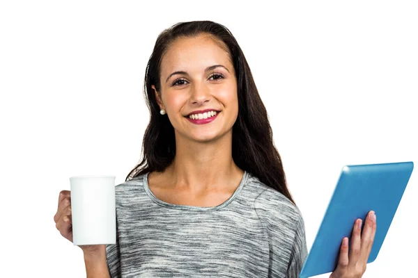 Улыбающаяся молодая женщина держит чашу и планшет — стоковое фото